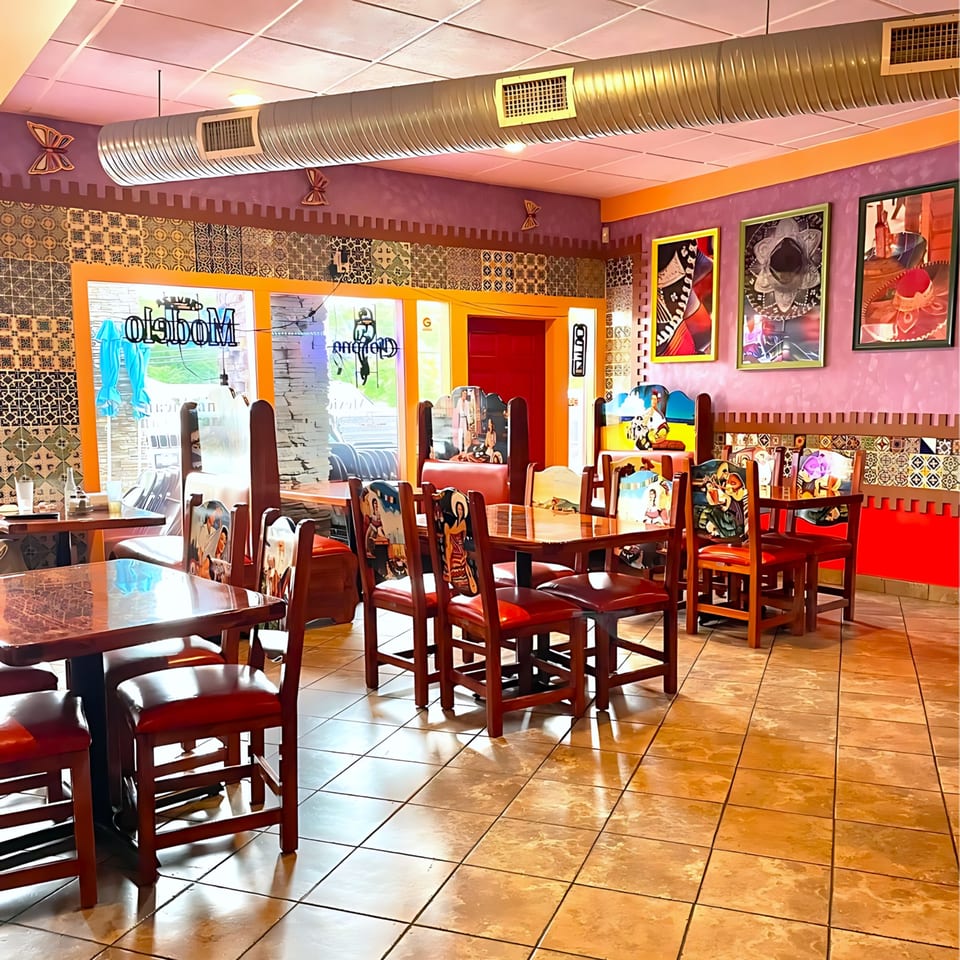 Colorful, empty dining room at Casa Vallarta with Mexican-themed chairs, tables, and decor.